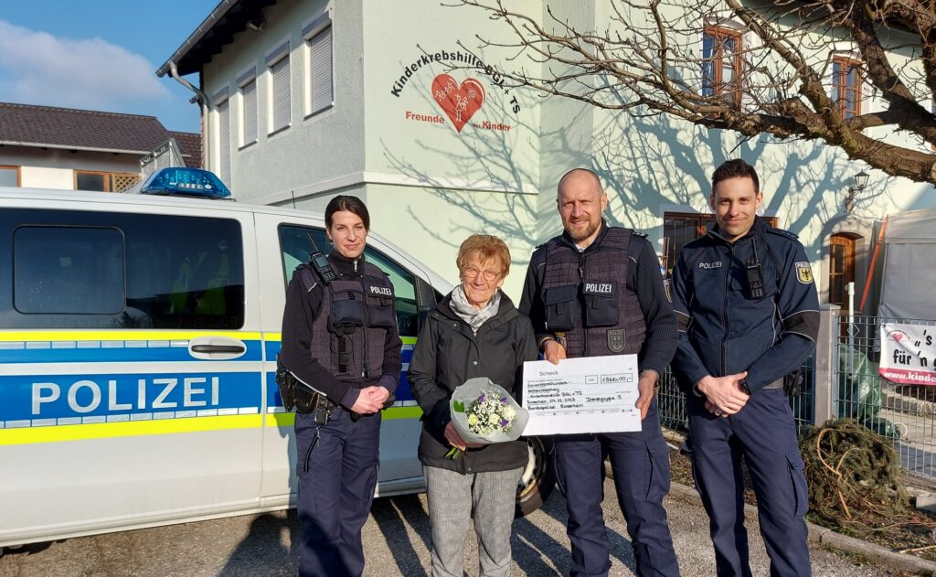 Vor dem Vereinsheim der Kinderkrebshilfe übergeben drei Beamte der Bundespolizeiinspektion Rosenheim den Spendenscheck an Rosmarie Baumgartner.