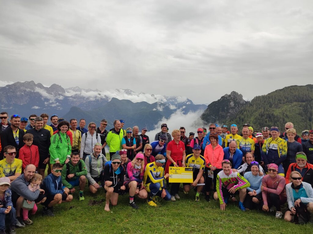 Die Teilnehmer der Thomas-Brengartner-Gedächtnisfahrt posieren vor Bergpanorama - die Spenden wird an Rosmarie Baumgartner für die Kinderkrebshilfe BGL+TS überreicht