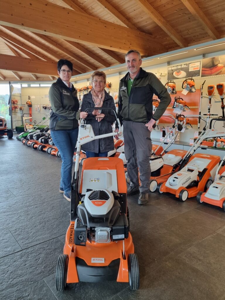 Andrea und Stefan Steinmassl überreichen Rosmarie Baumgartner, 1. Vorsitzende Kinderkrebshilfe BGL+TS, einen Rasenmäher als Spende für das Ferienhaus der Kinderkrebshilfe im Bayerischen Wald.