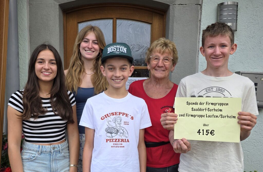 Die Firmlinge Bernadette Zillner, Julia Mayer, Sebastian Veiglhuber und Miche Langwieder überreichen 415 € an Rosmarie Baumgartner - das Foto wurde vor dem Eingang zum Vereinsheim der Kinderkrebshilfe aufgenommen.
