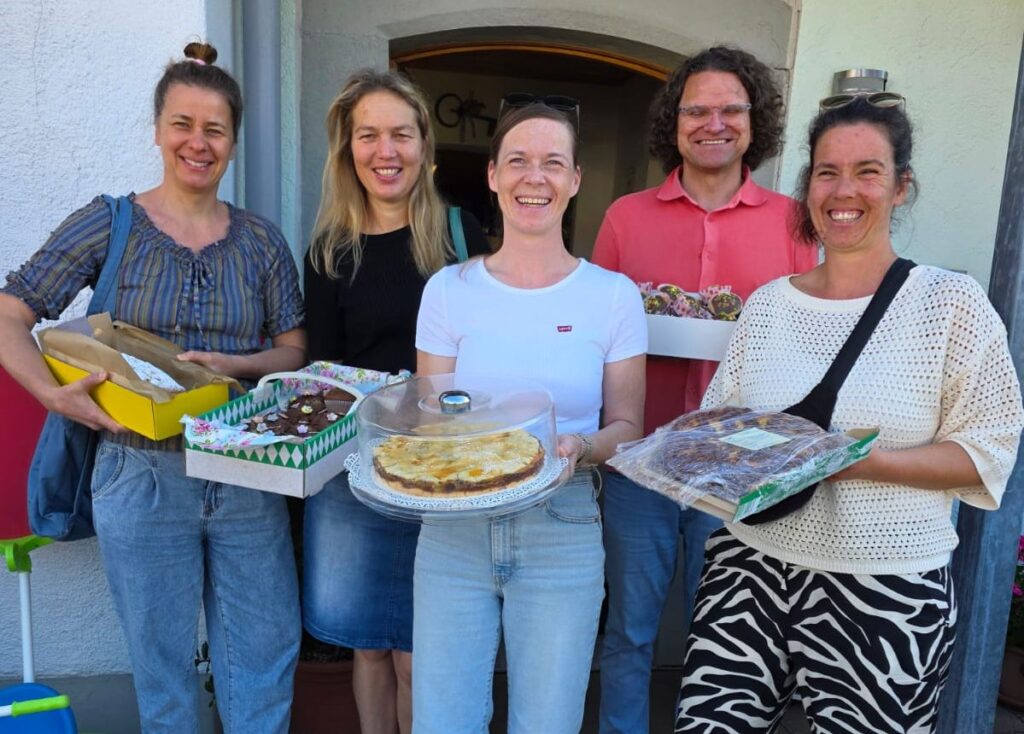 Eine "Abordnung" des Gymnasiums LSH Marquartstein steht, mit Kuchen in ihren Händen, vor der Eingangstür des Kaufhauses für 'n guadn Zweck in Oberteisendorf.